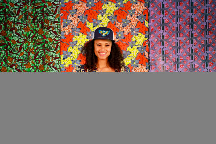 Satou Sabally in a colorful printed suit holding up a Dallas Wings jersey